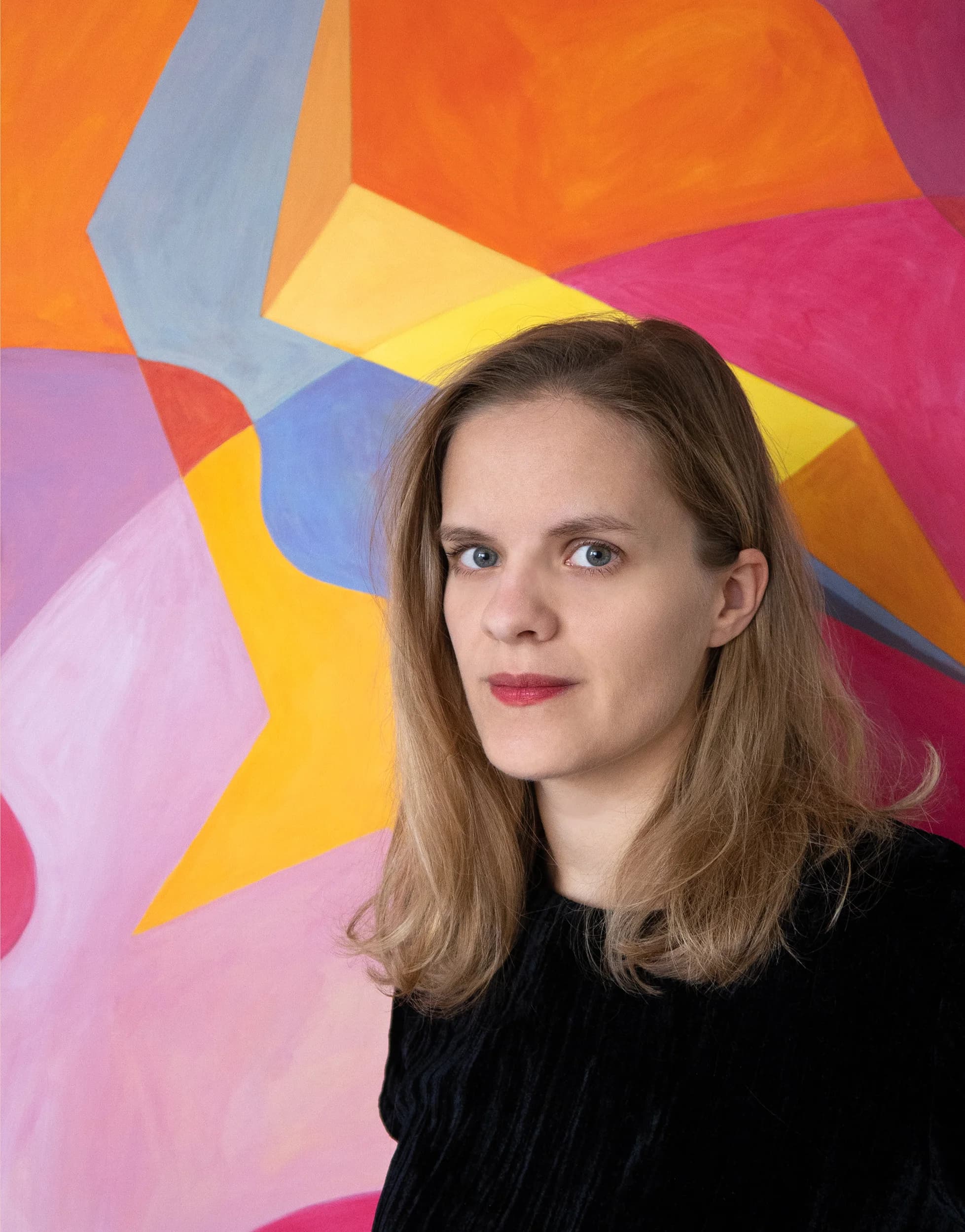 Portrait of Agata Pałach-Bożek in front of a colorful abstract painting.